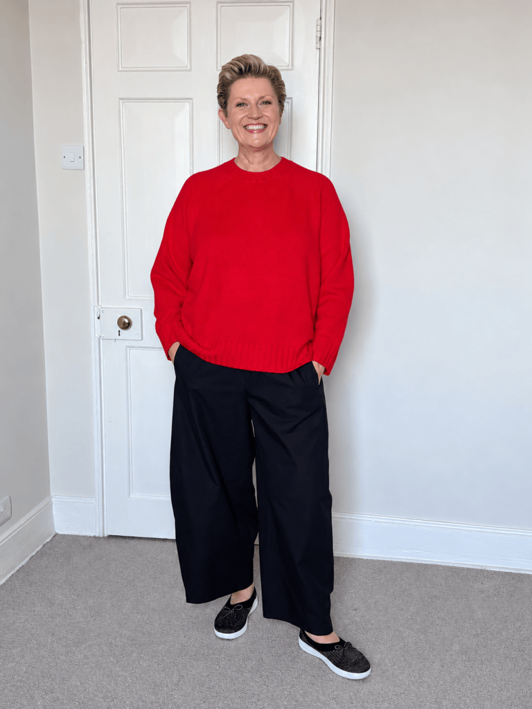 Susy wearing a bright red John Lewis jumper with black trousers