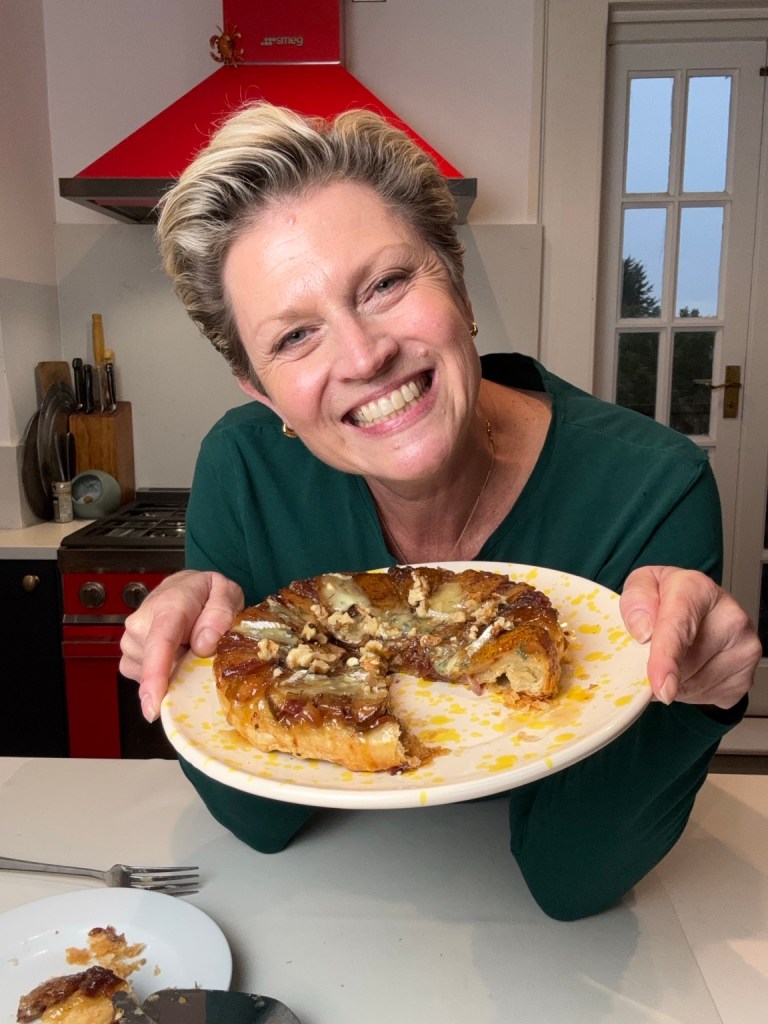 Susy Bortolot holding a homemade pear, blue cheese and figgy mustard tarte Tatin in her kitchen