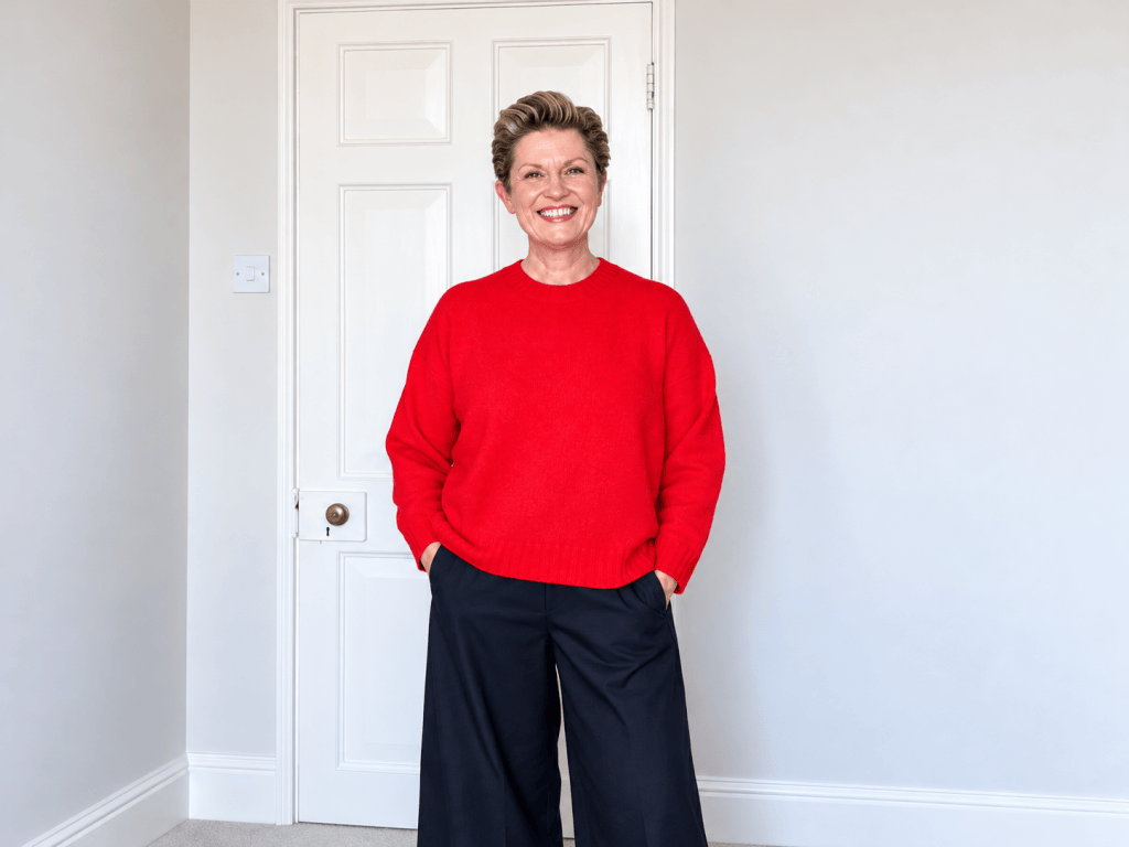 Susy wearing a bright red John Lewis jumper with black COS barrel-leg trousers
